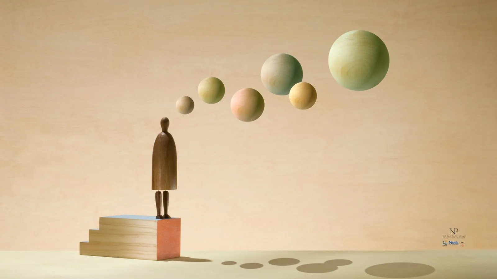 Una piccola figura di legno in cima a una scala di blocchi guarda una fila di sfere che si allontanano nell’aria, sempre più grandi