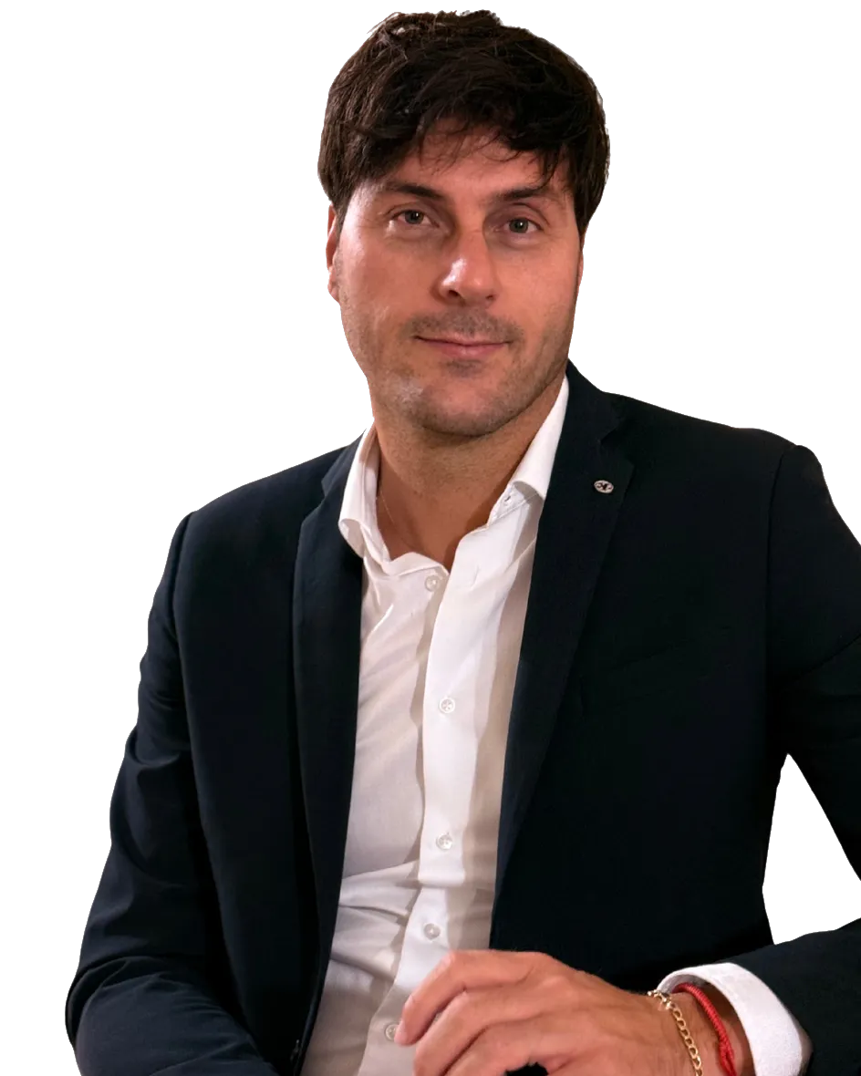 Ritratto di Nicola Parrinello, in giacca blu scuro e camicia bianca, seduto, con le mani appoggiate davanti a sé
